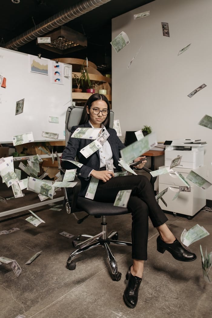 Offerings 3 woman sitting on an office chair with money flying all around her 7654610